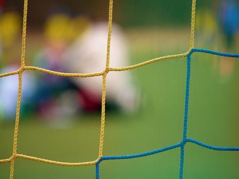 Football player stands against goal with net and stadium. Football gate net. Soccer gate net.  In blurry background stand people.