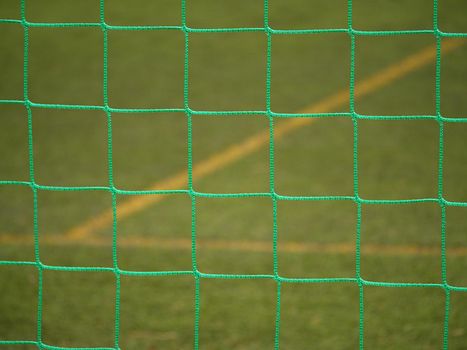 Detail of a soccer net against green grass on stadium. Selective focus with detailed knots