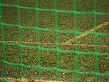 Close up detail of a soccer net against green grass on a cloudy day. Selective focus