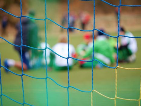Detail of a soccer net against green grass on stadium. Selective focus with detailed knots