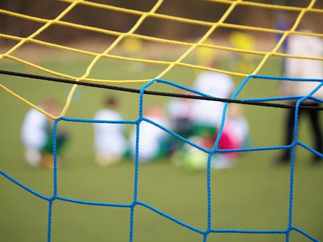 Football training.  Crossed soccer nets soccer football in goal net with grass on outdoor playground in the background.