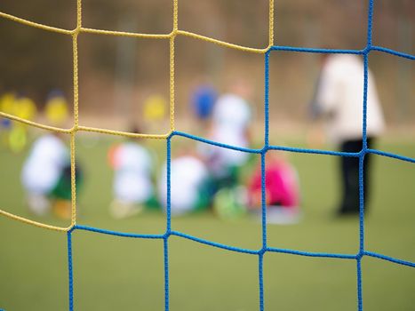 Football gate net. Soccer gate net. In blurry background stand players. Training of junior team. 