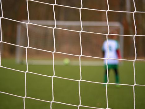 Footballists and stadium arena soccer field defocused. Vew through soccer gate net. 