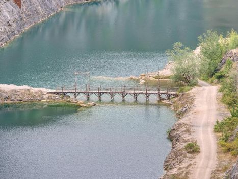 Green blue lake with wooden tourist path bridge above cold water. Hiking in the national park