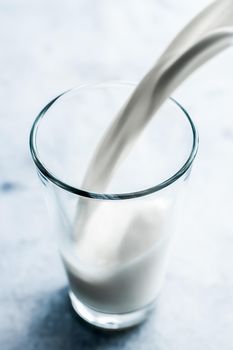 Dairy, healthy nutrition and breakfast concept - World Milk Day, pouring into glass on marble table