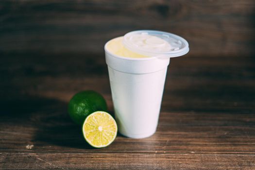 A disposable styrofoam cup and a citrus fruit