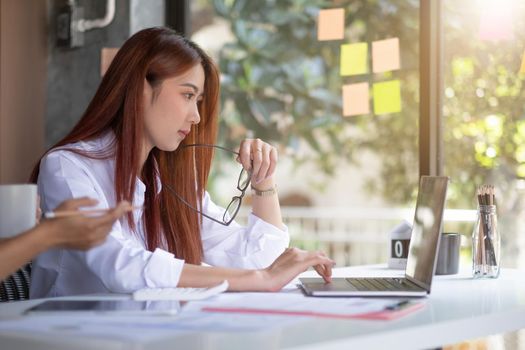 Concentrated young asian woman working on her computer. Start-up at home office.