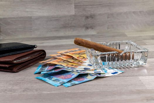20 and 50 euro banknotes and wallet and cigar on wood background
