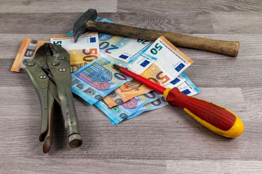 20 and 50 euro banknotes and work tools on wooden background