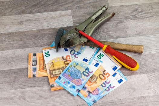 20 and 50 euro banknotes and work tools on wooden background