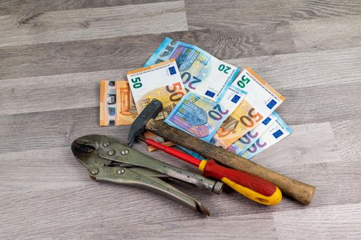 20 and 50 euro banknotes and work tools on wooden background