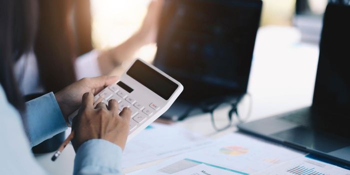 Group businessman hand using calculator to employees to increase productivity.Writing paper on desk.