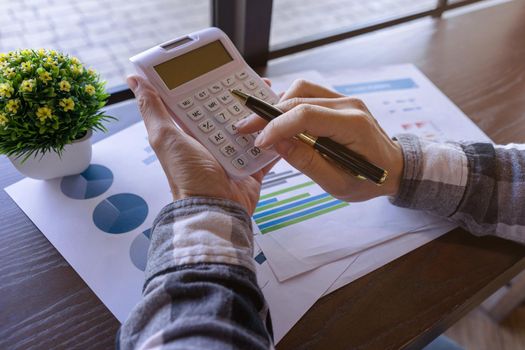 Businessman or Young freelance working with pen and pressing the calculator to calculate the accuracy of the investment budget. Freelance at work concept.