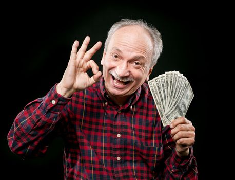 Happy elderly man showing fan of money and sign OK with fingers