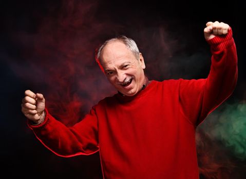 Successful old happy man in a red sweater gestures
