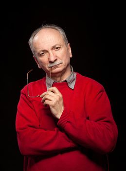 Portrait of a thoughtful elderly man with glasses in a red sweater
