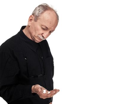 Medicine and health concept. Elderly man with pills in hands on a white background. Old man wants to take a pill