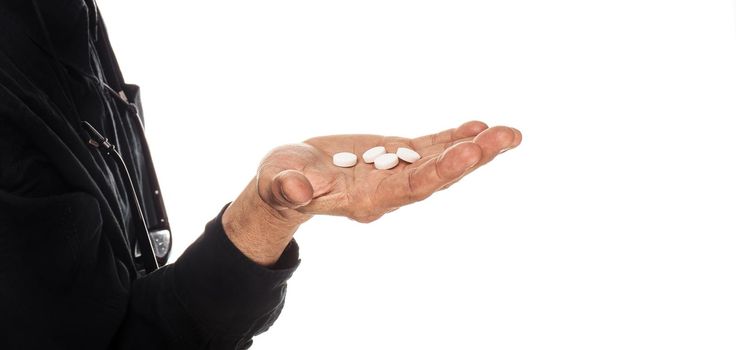 Medicine and health concept. Hand of an elderly man with pills on a white background. Old man wants to take a pill