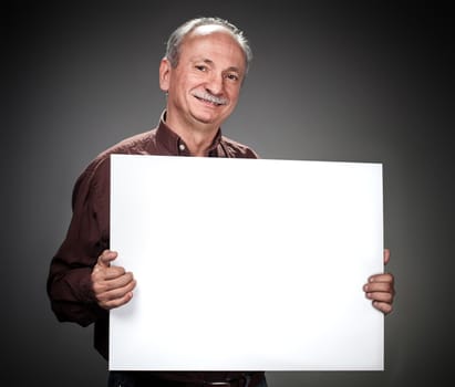 An elderly man holding a blank billboard