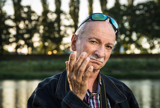 Life style concept. Old man. Portrait of a wise, skeptical and tired of life elderly man on a natural background