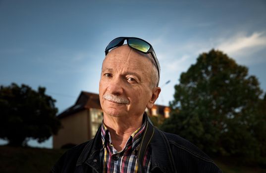 Life style concept. Old man. Portrait of a wise, skeptical and tired of life elderly man on a natural background