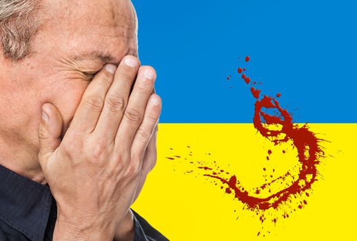 The war in Ukraine. Elderly man covered his face against the background of Ukrainian flag with blood stains