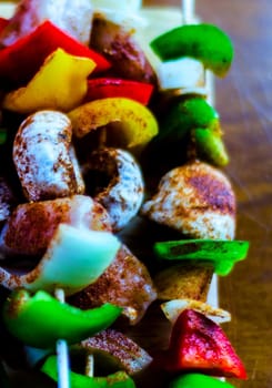 skewers with meat and vegetables prepared for grilling on a wooden board, colorful and tasty dish