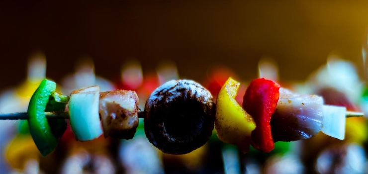 skewers with meat and vegetables prepared for grilling on a wooden board, colorful and tasty dish