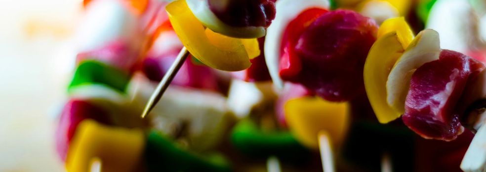 skewers with meat and vegetables prepared for grilling on a wooden board, colorful and tasty dish