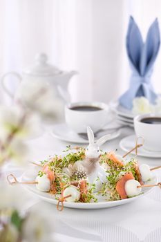 Appetizer quail egg stuffed with alfalfa sprouts with a slice of salmon, on a wooden skewer. Buffet serving for the Easter table.