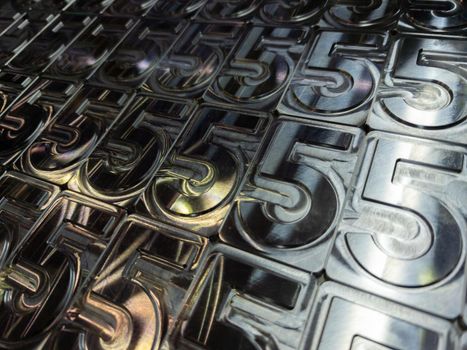 shiny metal machined digit 5 plates tiled tightly - close-up full frame background
