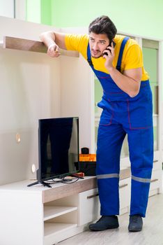 Male professional serviceman repairing tv at home