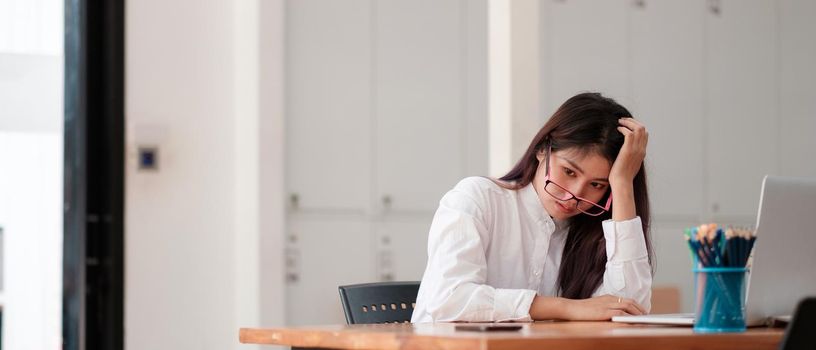 Bored asian female worker lie at office desk think about problem solution, unmotivated businesswoman search inspiration, tired of monotonous work. Lack of motivation concept