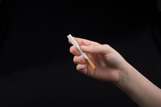 Hand is holding a cigarette on black background