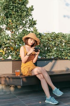 Fashionably dressed woman sitting outside and using camera