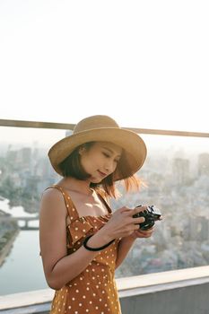 Young beautiful Asian traveler woman using digital compact camera and smile