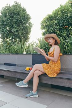 Cute young woman sitting in the park and reading the book