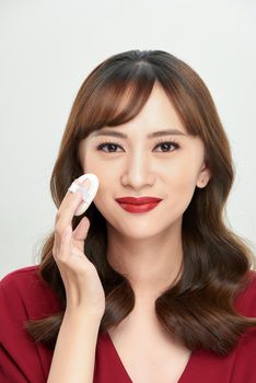 Makeup beauty Asian woman applying powder foundation on face.