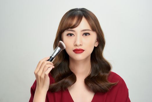 Beauty Asian Girl tan skin with Makeup Brushes. She smiling and looking to powder brush, Natural makeup