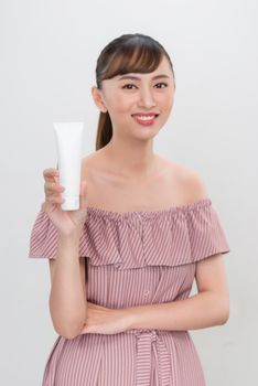 Portrait beautiful asian woman showing product with white cosmetic tube plastic