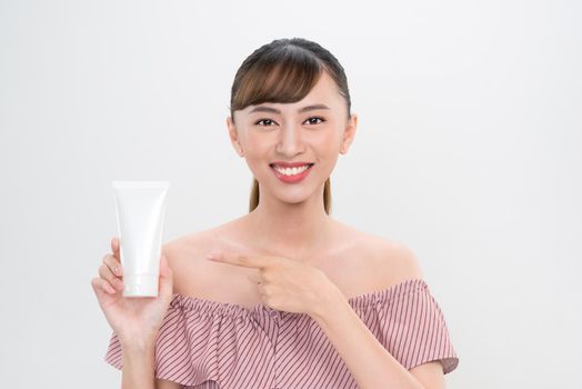 smiling young woman showing skincare products 