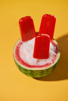 Watermelon popsicle sticks over yellow background, summer mood