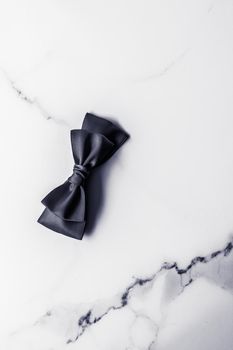 Holiday gift, decoration and sale promotion concept - Black silk ribbon and bow on marble background, flatlay