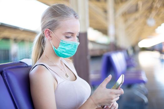 young woman with face mask waiting in vintage train, relaxed and carefree at the station platform in Bangkok, Thailand before catching a train. Travel photography. Lifestyle.