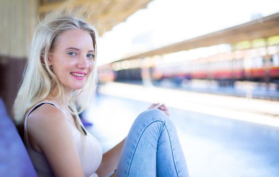 young woman waiting in vintage train, relaxed and carefree at the station platform in Bangkok, Thailand before catching a train. Travel photography. Lifestyle.