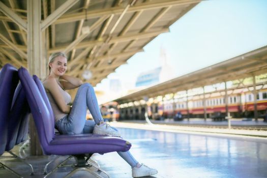 young woman waiting in vintage train, relaxed and carefree at the station platform in Bangkok, Thailand before catching a train. Travel photography. Lifestyle.