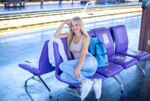 young woman waiting in vintage train, relaxed and carefree at the station platform in Bangkok, Thailand before catching a train. Travel photography. Lifestyle.