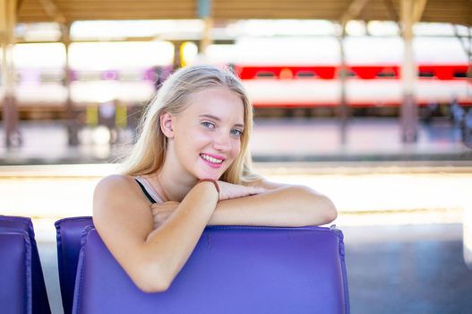 young woman waiting in vintage train, relaxed and carefree at the station platform in Bangkok, Thailand before catching a train. Travel photography. Lifestyle.