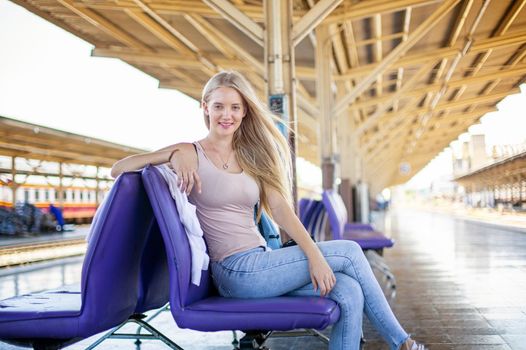 young woman waiting in vintage train, relaxed and carefree at the station platform in Bangkok, Thailand before catching a train. Travel photography. Lifestyle.