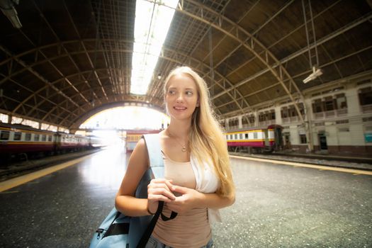 young woman waiting in vintage train, relaxed and carefree at the station platform in Bangkok, Thailand before catching a train. Travel photography. Lifestyle.